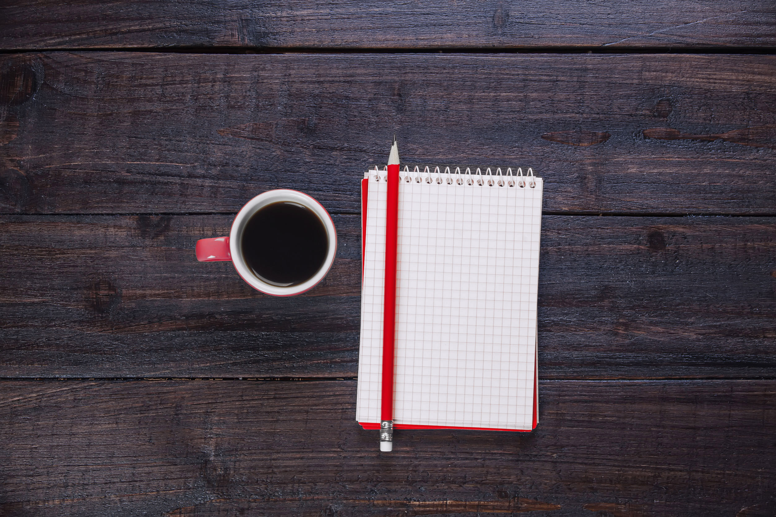 Kaffee und Notizbuch auf dunklem Holztisch